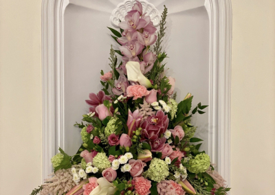 Floral pedestal with pink and greenery.